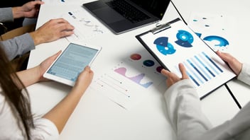 People hold papers with pie charts as they review market trends.