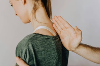  A healthcare professional examining a patient's upper back and neck, symbolizing the precise care required for spinal leak treatments, such as epidural blood patches, which anesthesiologists perform to manage spinal leaks.